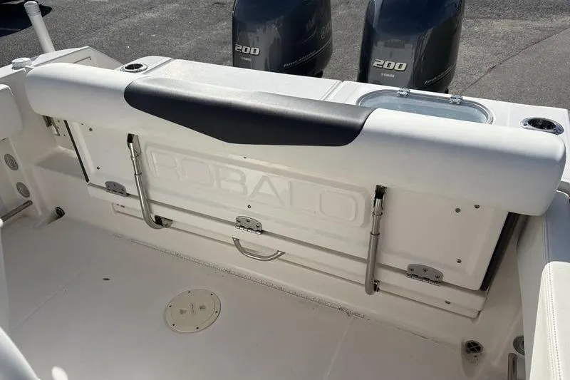 Slide: The Image of 2022 Robalo R242 Center Console T-top with rod holders against blue sky. - 12