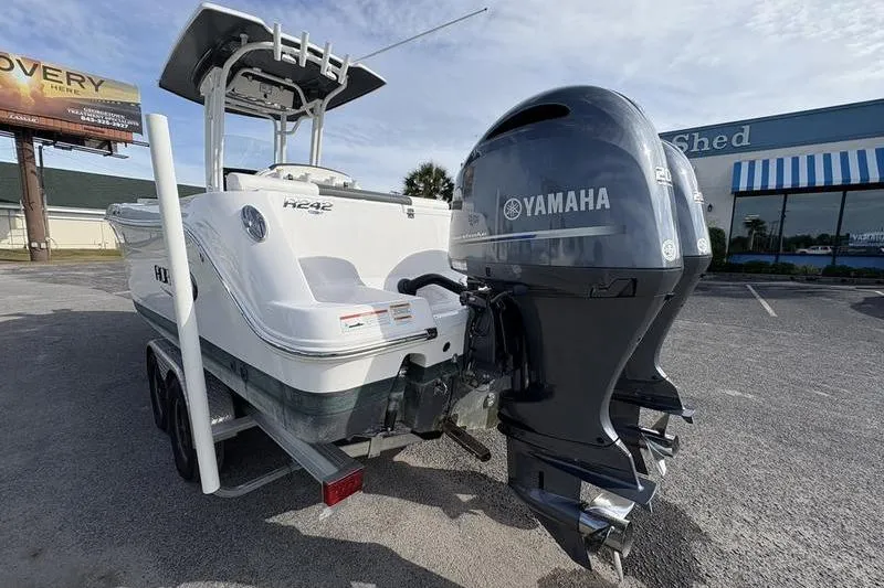 Slide: The Image of 2022 Robalo R242 Center Console with twin Yamaha 200 engines, parked outdoors. - 2