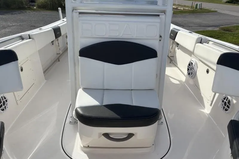 Slide: The Image of 2022 Robalo R242 Center Console boat with T-top, parked outdoors under a blue sky. - 27