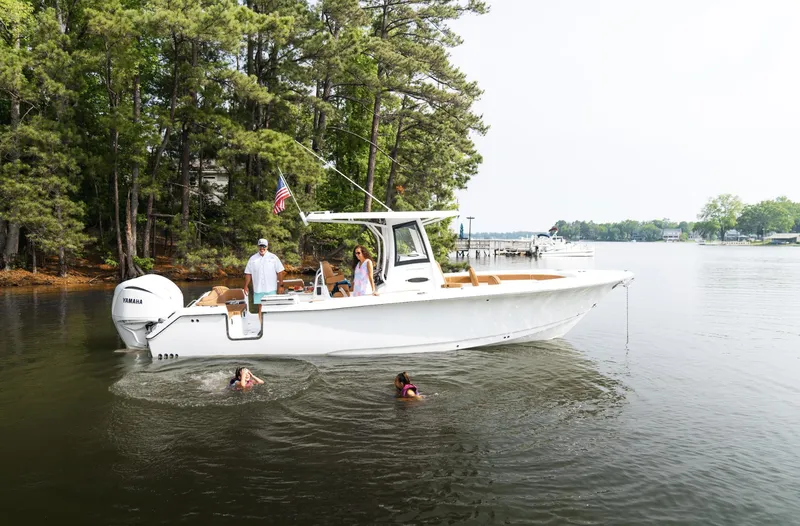 Slide: The Image of 2025 Sea Hunt Ultra 305 SE boat on a serene lake with swimmers nearby. - 20