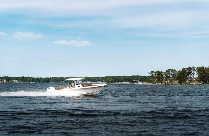 Slide: The Image of 2025 Sea Hunt Ultra 305 SE cruising on a serene lake under a clear blue sky. - 3
