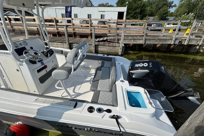 Slide: The Image of 2024 NauticStar 222OSL boat docked, featuring modern seating and powerful outboard motor. - 2