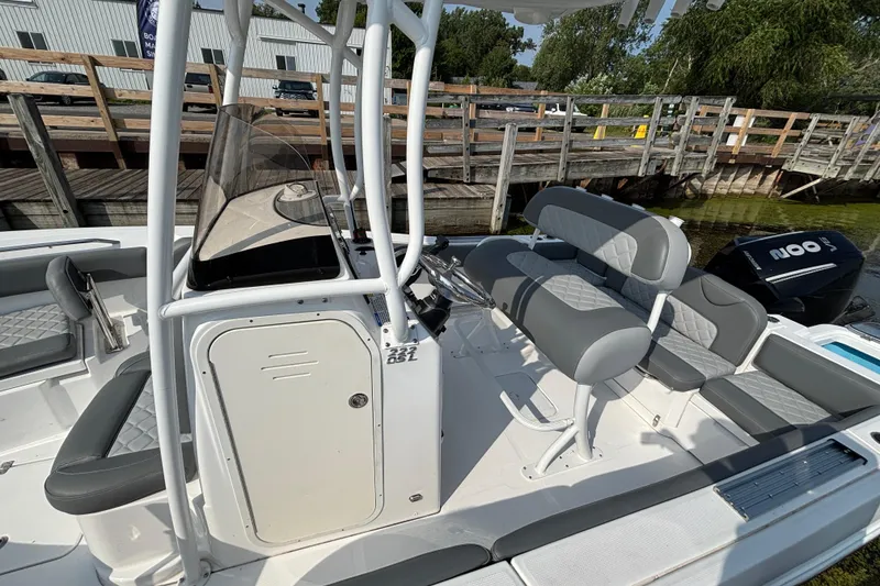 Slide: The Image of 2024 NauticStar 222OSL boat interior with seating and console, docked by wooden pier. - 5