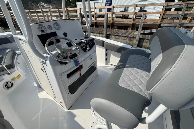 Slide: The Image of 2024 NauticStar 222OSL boat interior with steering console and cushioned seating. - 7