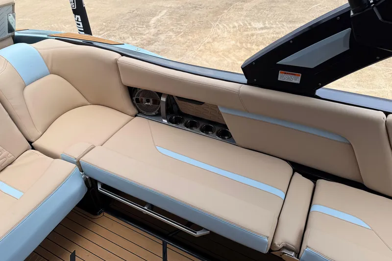 Slide: The Image of 2022 MasterCraft X24 boat interior with beige and blue seating, cup holders, and speaker. - 10