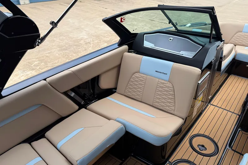 Slide: The Image of 2022 MasterCraft X24 boat interior with beige and blue seating, teak flooring. - 11