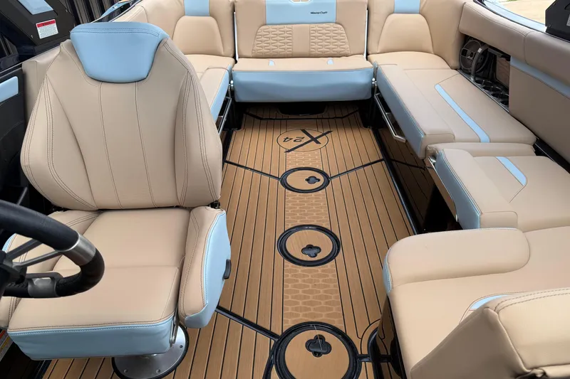 Slide: The Image of 2022 MasterCraft X24 boat interior with beige and blue seating, teak-style flooring. - 17