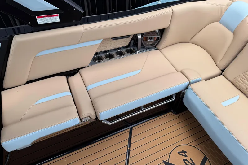 Slide: The Image of 2022 MasterCraft X24 boat interior with beige and blue seating, cup holders, and speaker. - 8