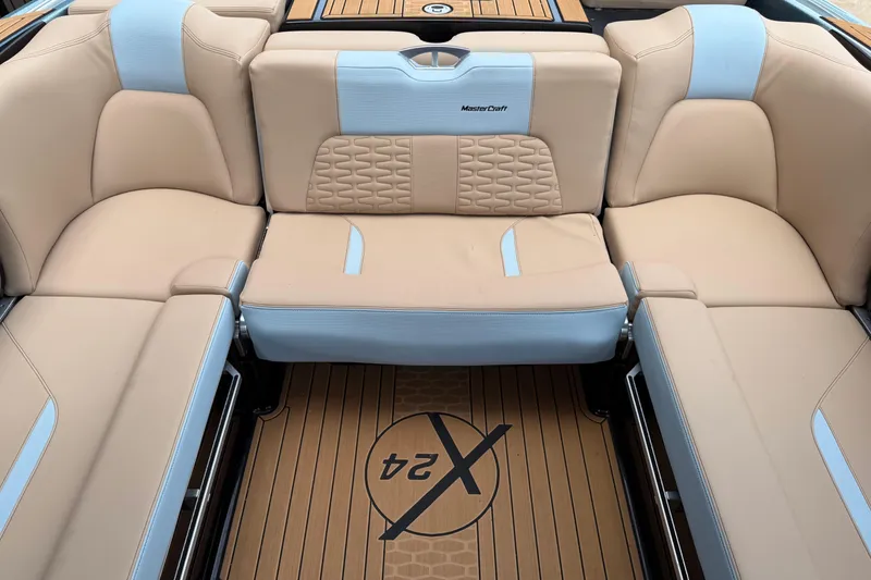 Slide: The Image of 2022 MasterCraft X24 boat interior with beige and blue seating, featuring logo on floor. - 9