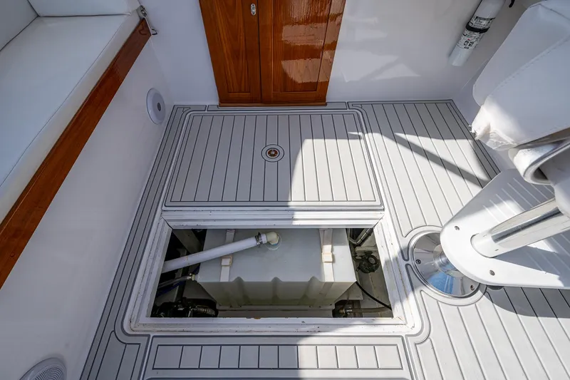 Slide: The Image of 2019 Custom Carolina Custom Express boat deck with open hatch, revealing storage compartment. - 23