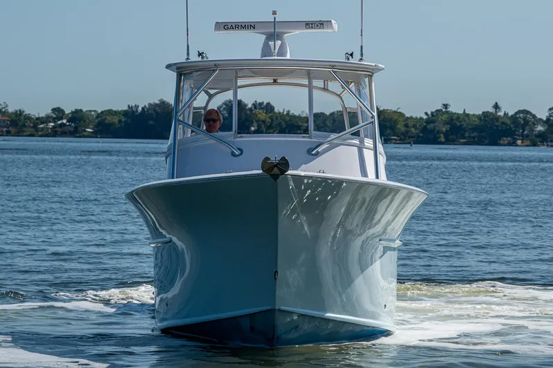 Slide: The Image of 2019 Custom Carolina Custom Express boat cruising on a calm lake. - 37
