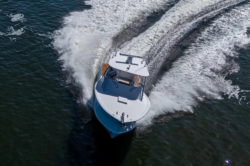 Slide: The Image of 2019 Custom Carolina Custom Express boat cruising on open water, creating a dynamic wake. - 6