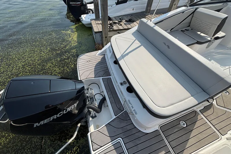 Slide: The Image of 2024 Sea Ray SPX 210 Outboard boat with Mercury engine, docked on calm water. - 2