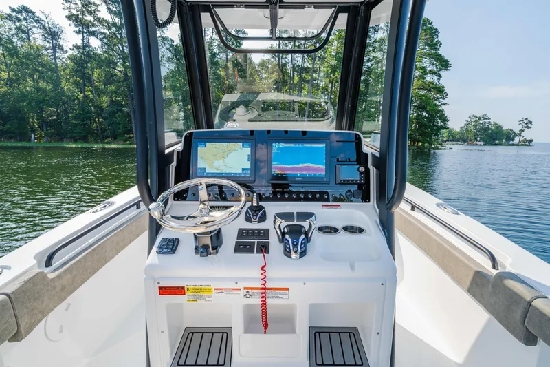 Slide: The Image of 2026 Sea Hunt Gamefish 25 boat dashboard with navigation screens on a serene lake. - 15