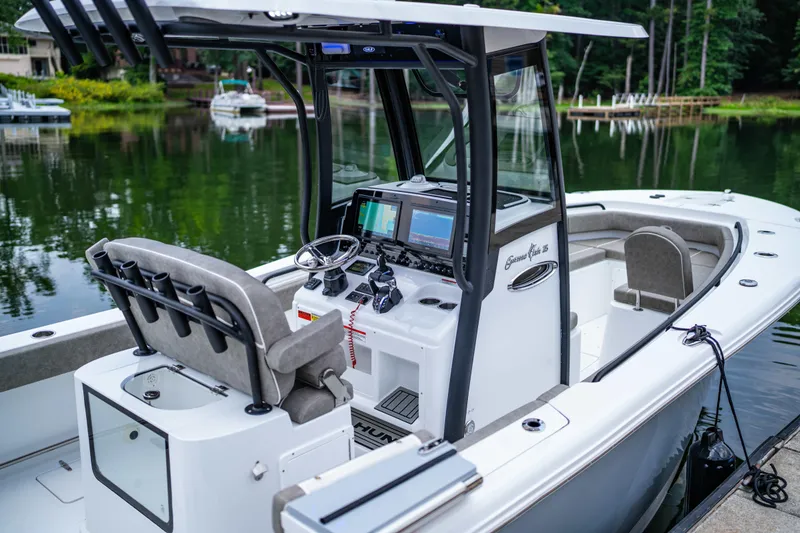Slide: The Image of 2026 Sea Hunt Gamefish 25 boat with modern console and seating, docked on a serene lake. - 19