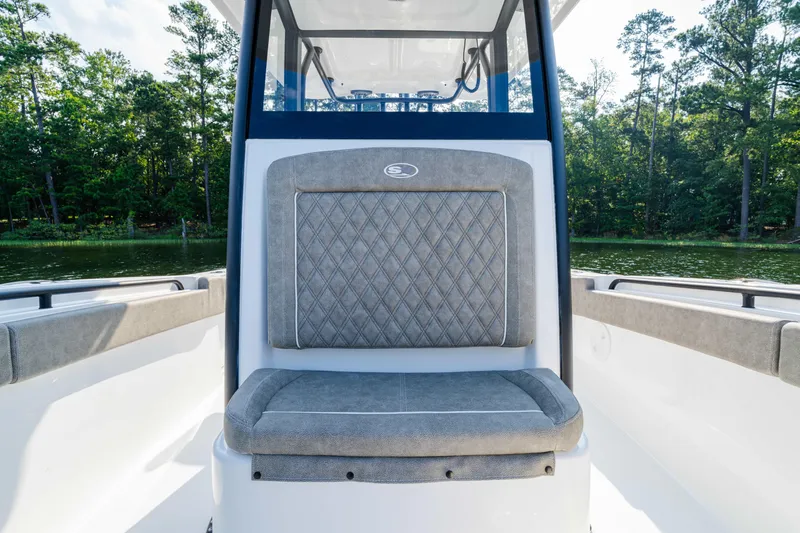 Slide: The Image of 2026 Sea Hunt Gamefish 25 boat interior with cushioned seating, surrounded by lush greenery. - 7