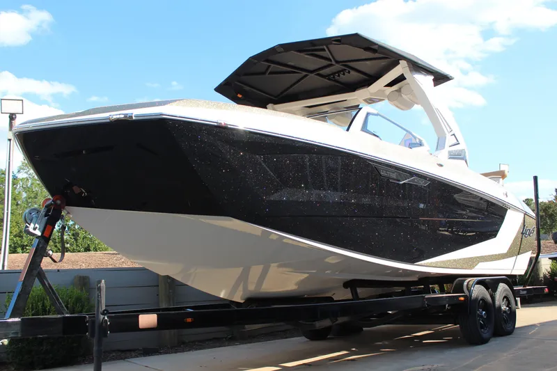 Slide: The Image of 2026 Tigé Ultré 25ZX boat on trailer, sleek black and white design, sunny day. - 17