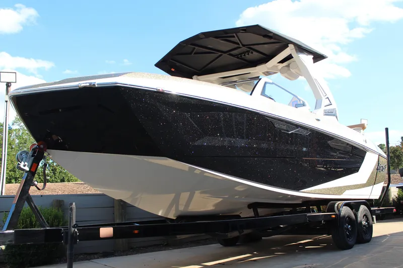 Slide: The Image of 2026 Tigé Ultré 25ZX boat on trailer, sleek black and white design, sunny day. - 18