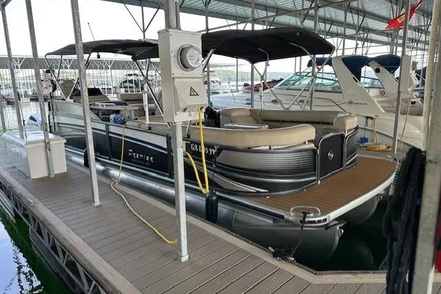 Slide: The Image of 2019 Premier 290 Grand View pontoon boat docked in a marina under a covered slip. - 20