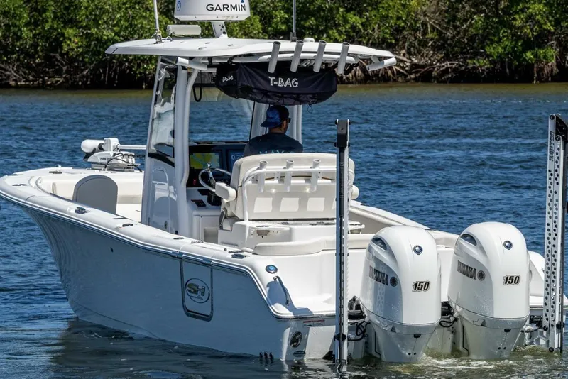 Slide: The Image of 2022 Sea Hunt Ultra 265 SE boat with dual Yamaha engines on a calm waterway. - 12