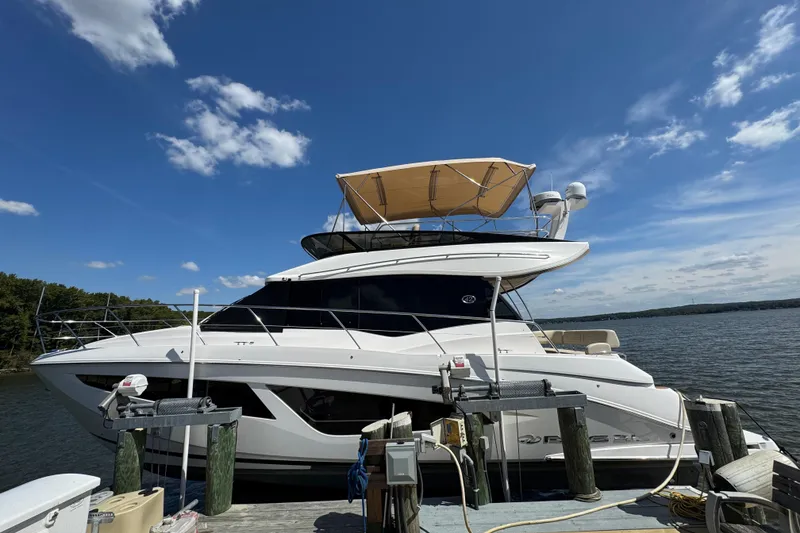 The Image of 2019 Regal 42 Fly yacht docked by a serene lake under a clear blue sky. - 0