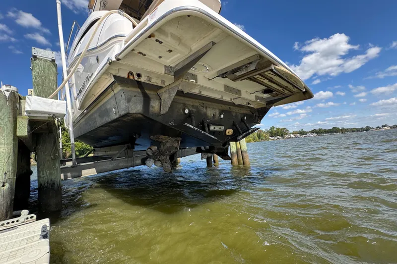 Slide: The Image of 2019 Regal 42 Fly yacht on lift, showcasing hull and propeller, against a scenic waterfront. - 13