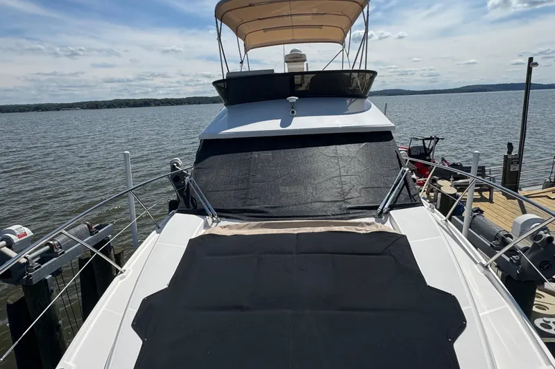 Slide: The Image of 2019 Regal 42 Fly yacht docked by the water, featuring a spacious deck and canopy. - 14