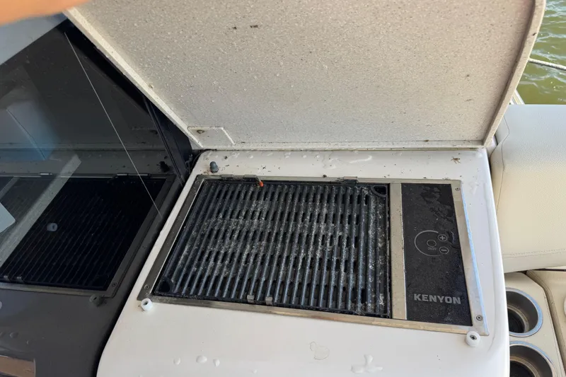Slide: The Image of Kenyon grill on 2019 Regal 42 Fly yacht, open lid, near water. - 16