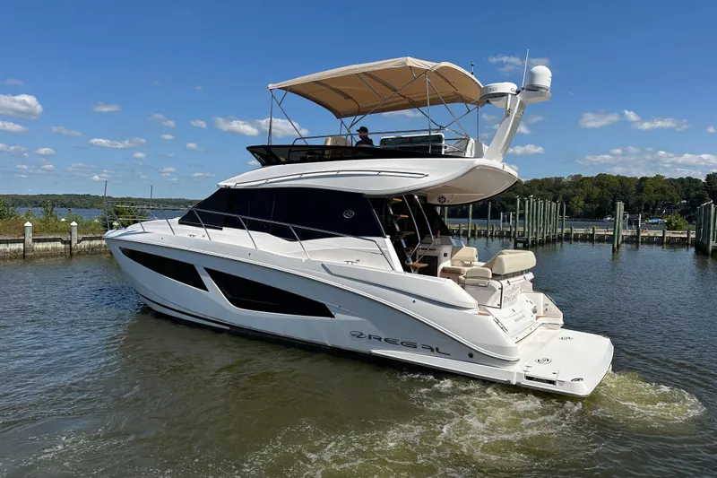 Slide: The Image of 2019 Regal 42 Fly yacht cruising on a sunny day near a marina. - 2