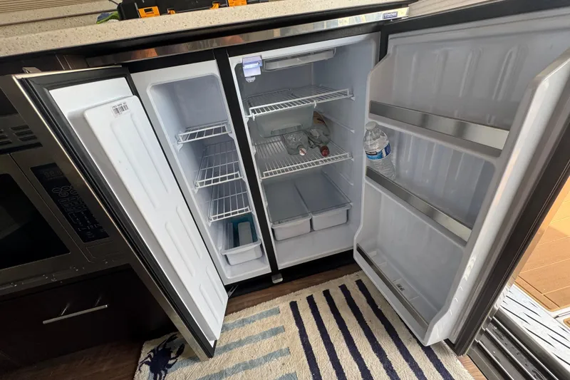 Slide: The Image of Open refrigerator on a 2019 Regal 42 Fly yacht, showing shelves and bottled water. - 20