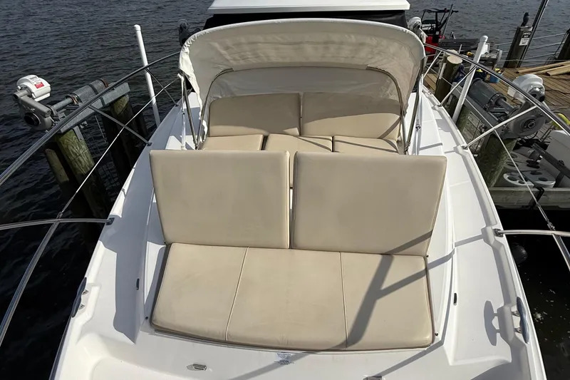 Slide: The Image of 2019 Regal 42 Fly yacht with beige cushioned seating on deck, docked by the water. - 7