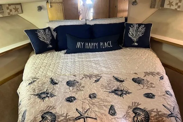 Slide: The Image of Cozy cabin bedroom in 1998 Tiara Yachts 3500 Open, featuring nautical-themed bedding. - 3