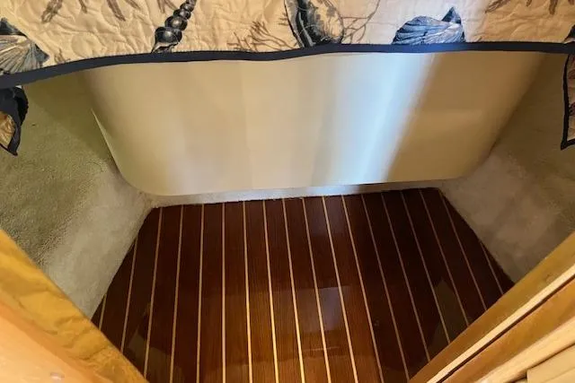 Slide: The Image of 1998 Tiara Yachts 3500 Open cabin interior with polished wood flooring and nautical-themed bedding. - 40