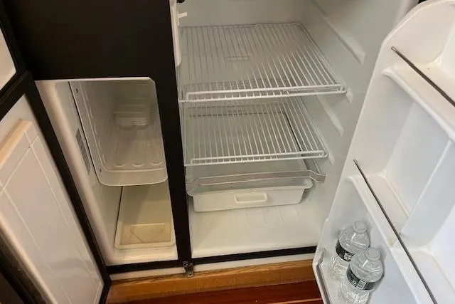 Slide: The Image of Open refrigerator inside 1998 Tiara Yachts 3500 Open, featuring empty shelves and bottled water. - 43