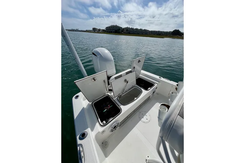 Slide: The Image of 2022 BlackJack 224 boat with open storage compartments on calm water. - 10