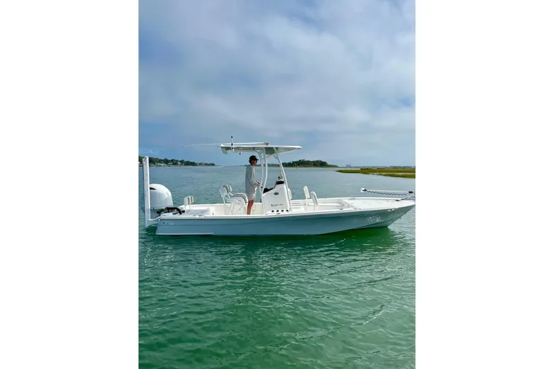 Slide: The Image of 2022 BlackJack 224 boat on calm water with a person standing onboard. - 2