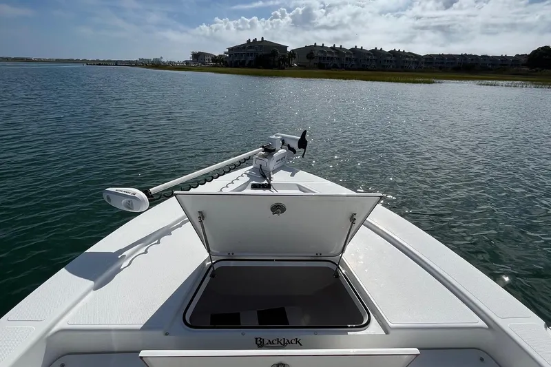 Slide: The Image of Bow of 2022 BlackJack 224 boat with open hatch, on calm water near shoreline. - 5