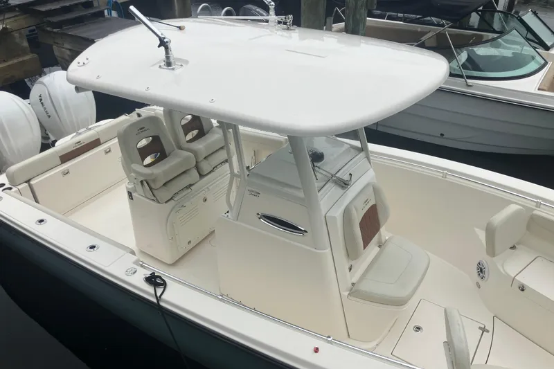 Slide: The Image of 2024 Cobia 280 Center Console boat with dual Yamaha engines, docked at a marina. - 2