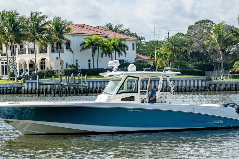 The Image of 2011 Boston Whaler 370 Outrage boat cruising near waterfront homes and palm trees. - 1