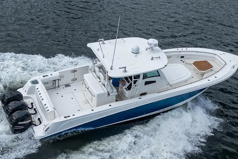 Slide: The Image of 2011 Boston Whaler 370 Outrage cruising on water, featuring triple Mercury engines. - 16