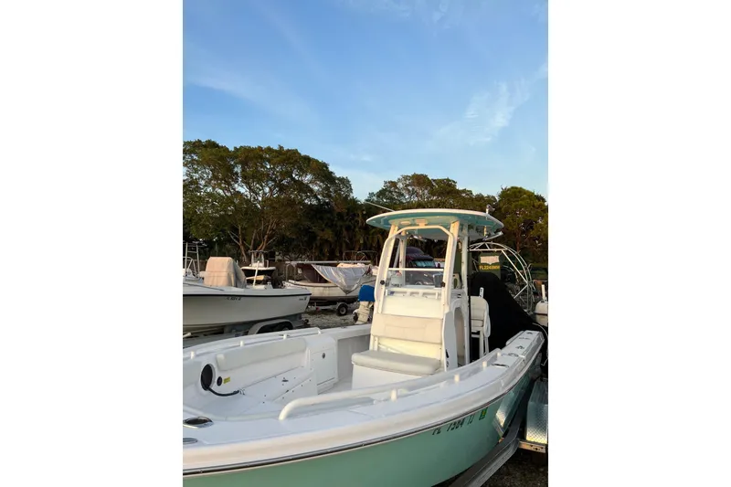 Slide: The Image of 2022 Everglades 243 Center Console boat docked, surrounded by trees and other boats. - 10