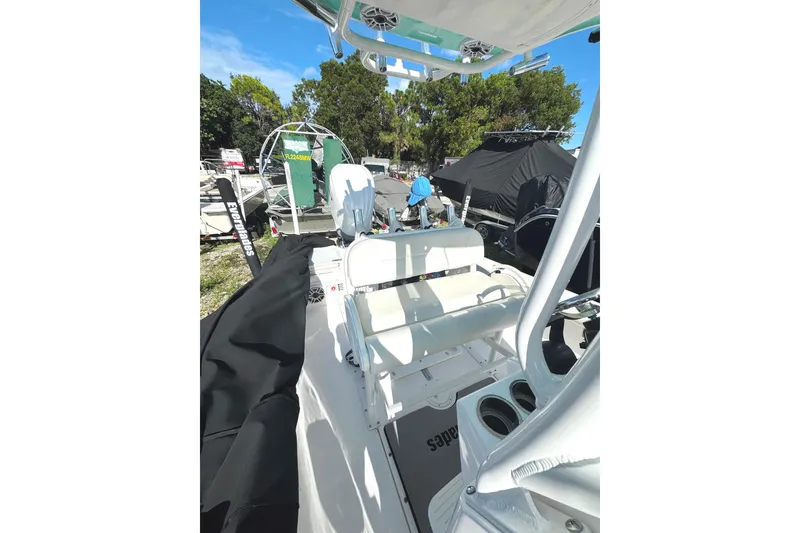 Slide: The Image of 2022 Everglades 243 Center Console boat, white interior, parked outdoors, surrounded by trees. - 18
