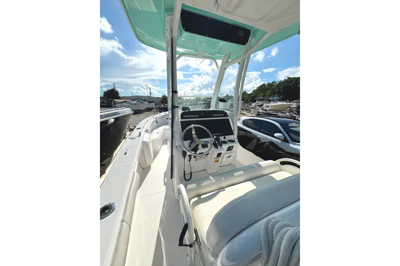 Slide: The Image of 2022 Everglades 243 Center Console boat interior with steering wheel and controls, under sunny sky. - 19