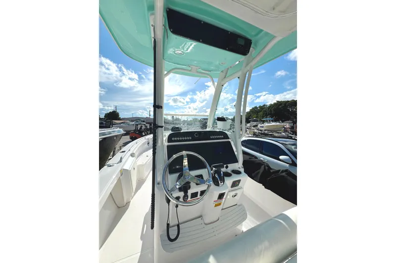Slide: The Image of 2022 Everglades 243 Center Console boat interior with steering wheel and controls under blue sky. - 20
