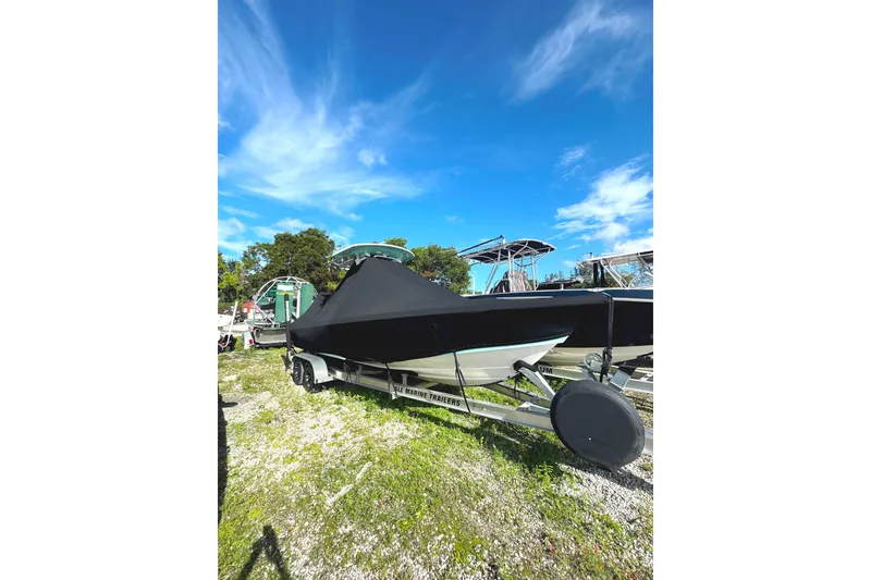 Slide: The Image of 2022 Everglades 243 Center Console boat covered on trailer under clear blue sky. - 32