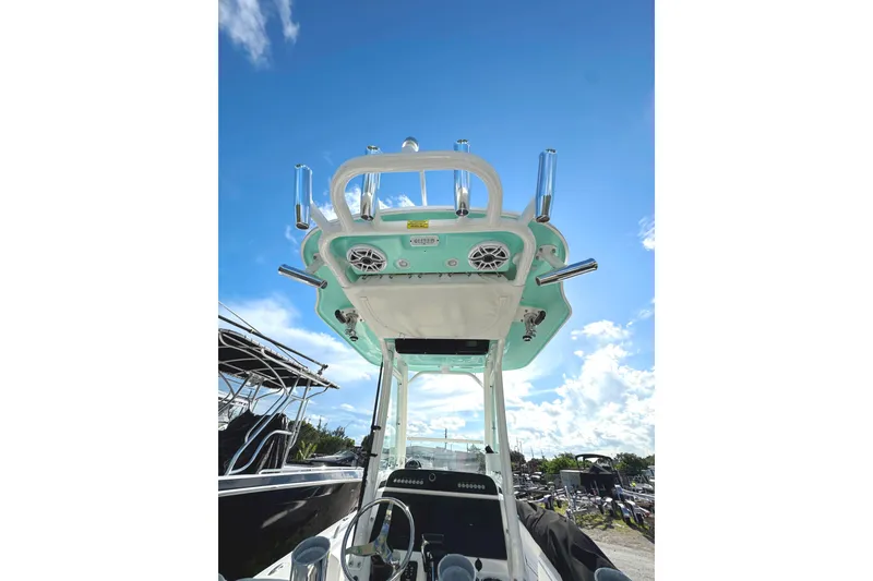 Slide: The Image of 2022 Everglades 243 Center Console boat with T-top and rod holders under a clear blue sky. - 6