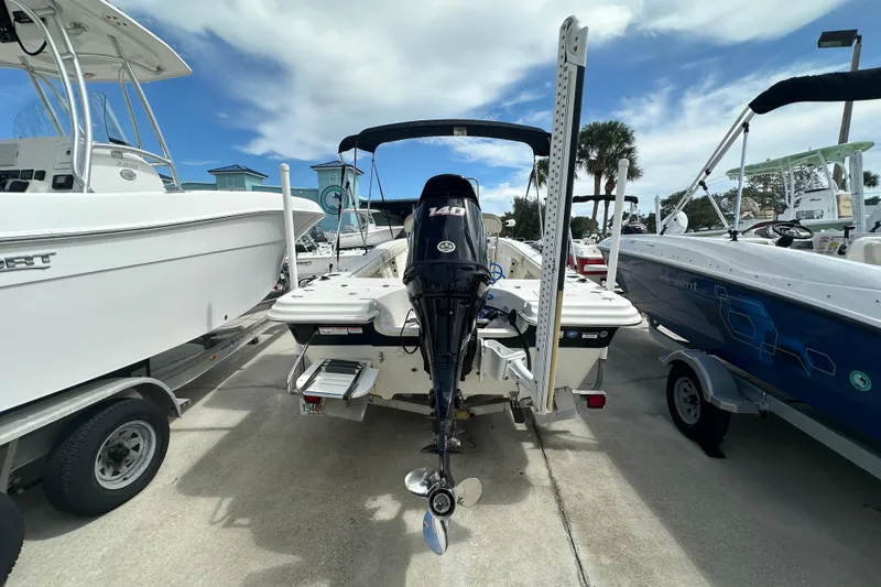 Slide: The Image of 2017 Carolina Skiff 21 Sea Skiff boat with outboard motor, parked between other boats. - 4
