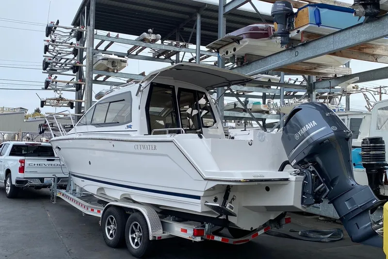 Slide: The Image of 2021 Cutwater C-24 Coupe boat on trailer, Yamaha outboard, parked near Chevrolet truck. - 0