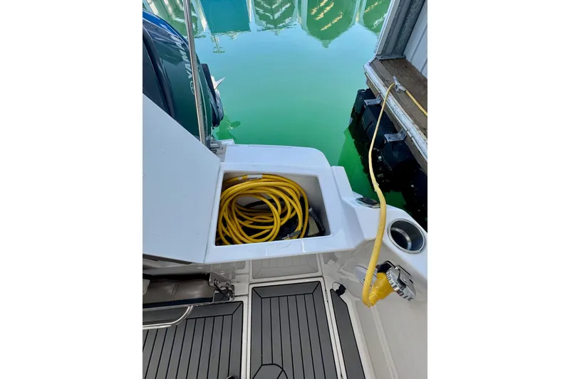 Slide: The Image of 2021 Cutwater C-24 Coupe boat with storage compartment and yellow cable at dock. - 15
