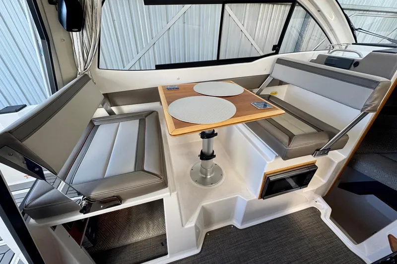 Slide: The Image of 2021 Cutwater C-24 Coupe interior with dining area, featuring cushioned seating and a wooden table. - 21